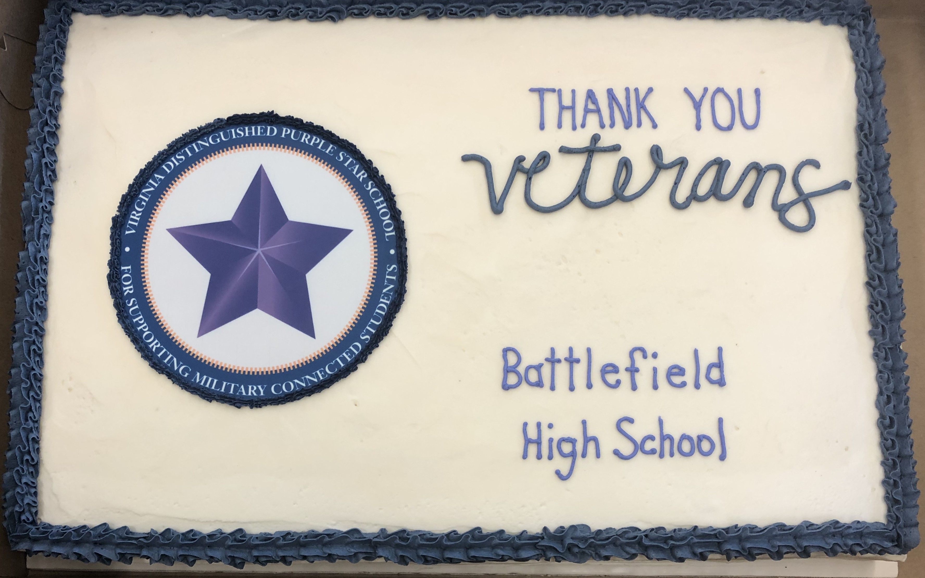 Cake with white icing and blue accent. with Thank You Veterans written on it in blue icing